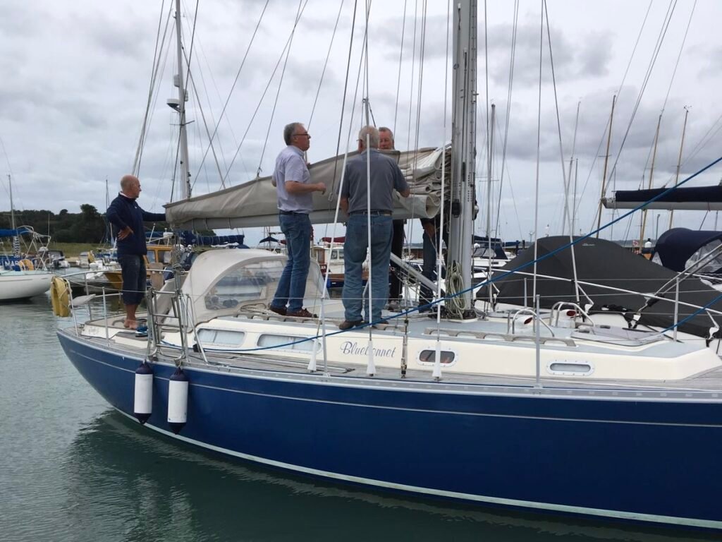 Corporate team members preparing a sailing yacht at the dock, working together on lines and sails during a corporate sailing team-building experience.